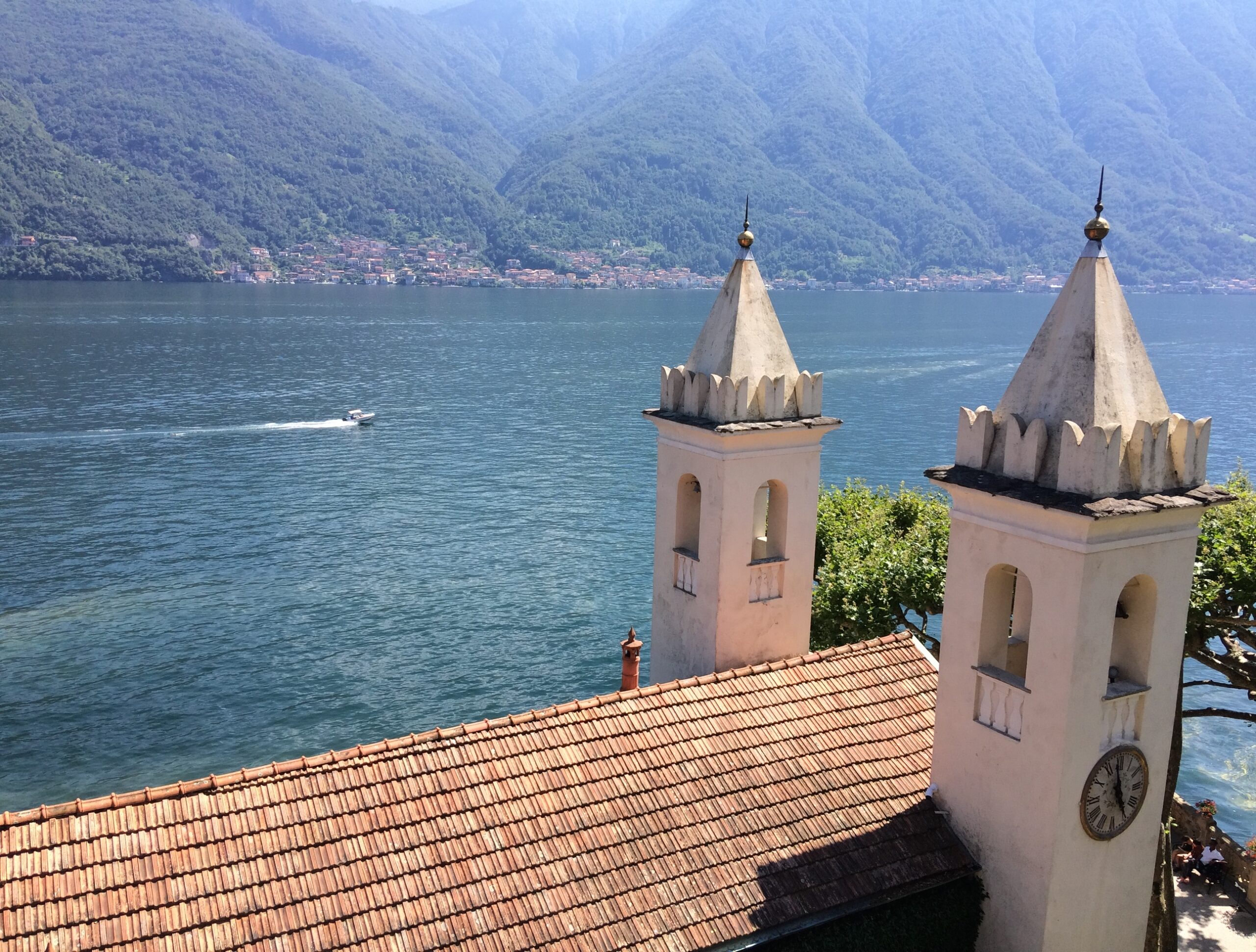 Vue sur le Lac de Côme en Italie, chapelle au premier plan, bateau à moteur seul sur l'eau en arrière plan