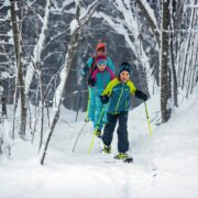 Famille dans la neige en skis de randonnée, équipée du pack youngstar