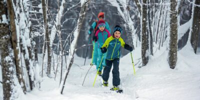 Famille dans la neige en skis de randonnée, équipée du pack youngstar